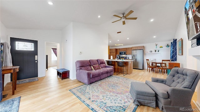 living room with a ceiling fan, high vaulted ceiling, recessed lighting, and light wood-type flooring