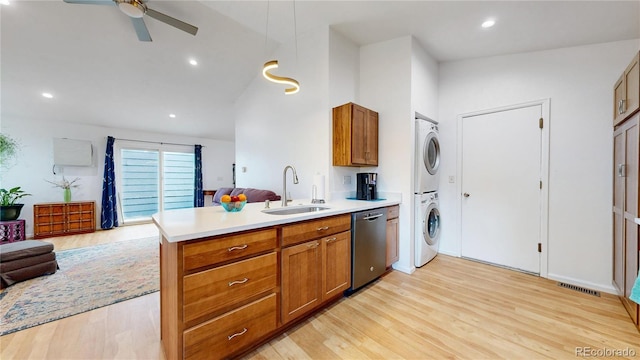 kitchen with a sink, stainless steel dishwasher, stacked washer / drying machine, and brown cabinetry