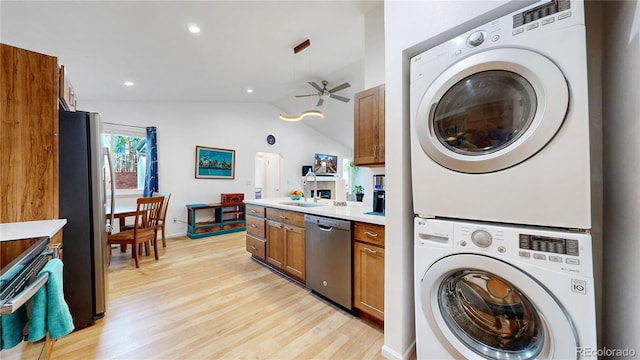 washroom featuring laundry area, stacked washer and clothes dryer, light wood finished floors, and a ceiling fan