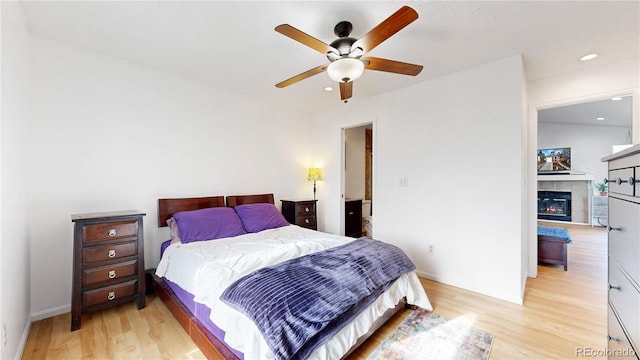 bedroom featuring a tiled fireplace, recessed lighting, light wood finished floors, and a ceiling fan