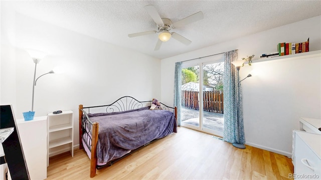 bedroom with access to outside, a textured ceiling, and light wood-style flooring