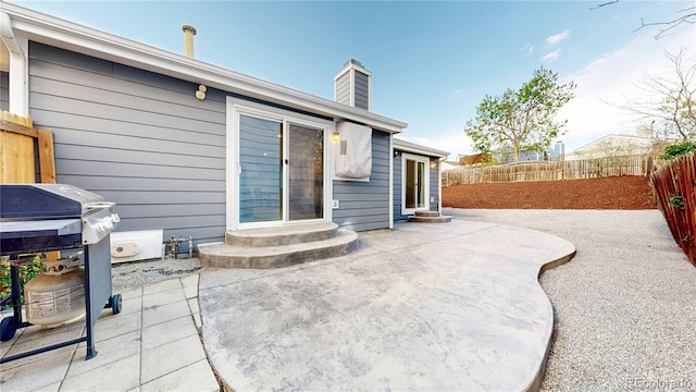 back of house with a fenced backyard, a patio area, a chimney, and entry steps