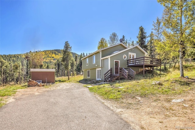 32252 Steven Way, Conifer, CO 80433 - view of front of property with a deck with mountain view, a shed, and dirt driveway