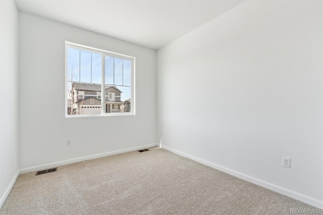 spare room with carpet flooring, baseboards, and visible vents