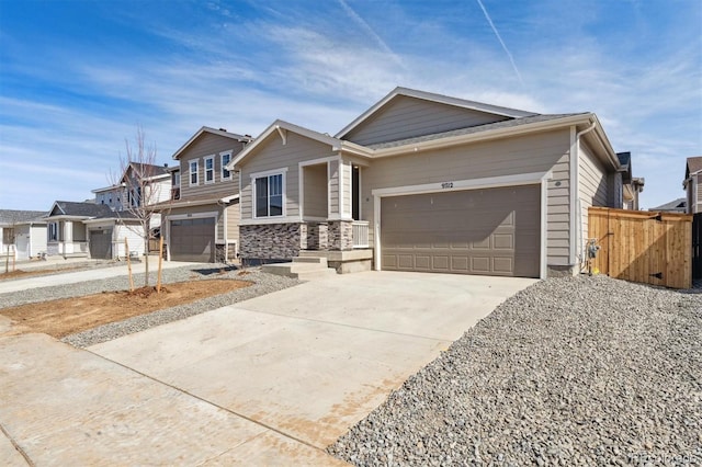 view of front of property with a garage, stone siding, driveway, and fence