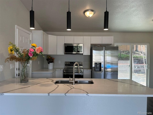 kitchen featuring pendant lighting, stainless steel appliances, white cabinets, and light stone countertops