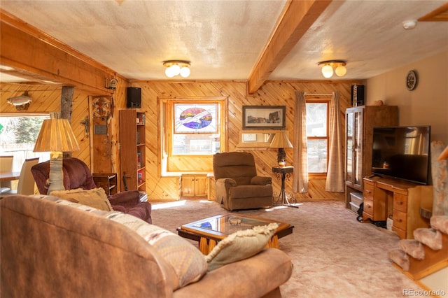 carpeted living room with beamed ceiling, wood walls, and a textured ceiling