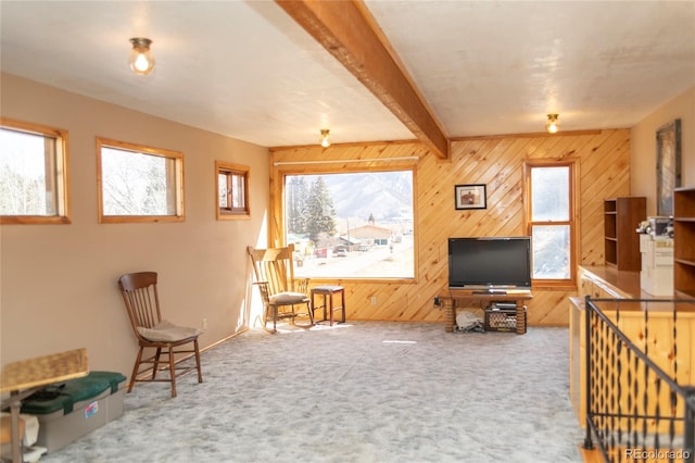 sitting room featuring beamed ceiling, wood walls, and carpet flooring