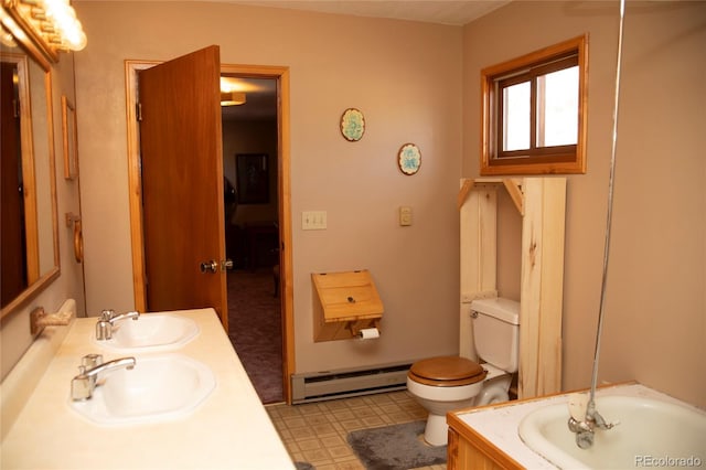 full bath featuring double vanity, toilet, a baseboard heating unit, and a sink