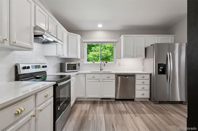9747 W Peakview Dr, Littleton, CO 80123 - kitchen featuring appliances with stainless steel finishes, under cabinet range hood, white cabinets, light wood-type flooring, and recessed lighting