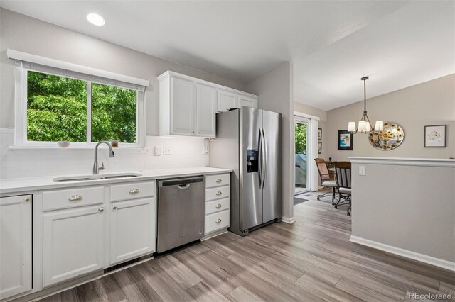 9747 W Peakview Dr, Littleton, CO 80123 - kitchen featuring stainless steel appliances, lofted ceiling, white cabinetry, light wood finished floors, and decorative backsplash