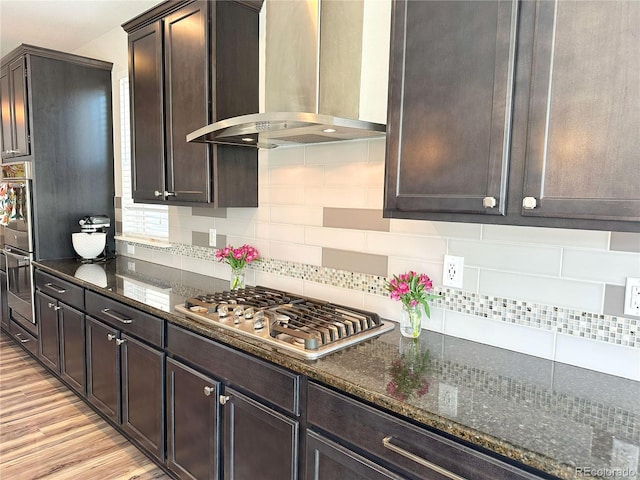 9482 Kendrick Way, Arvada, CO 80007 - kitchen with wall chimney exhaust hood, appliances with stainless steel finishes, dark brown cabinetry, and dark stone countertops
