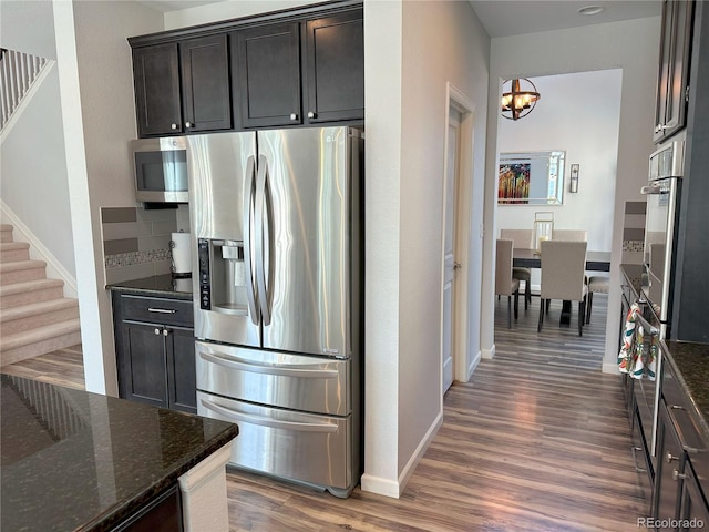 9482 Kendrick Way, Arvada, CO 80007 - kitchen with appliances with stainless steel finishes, wood finished floors, a chandelier, dark stone counters, and baseboards