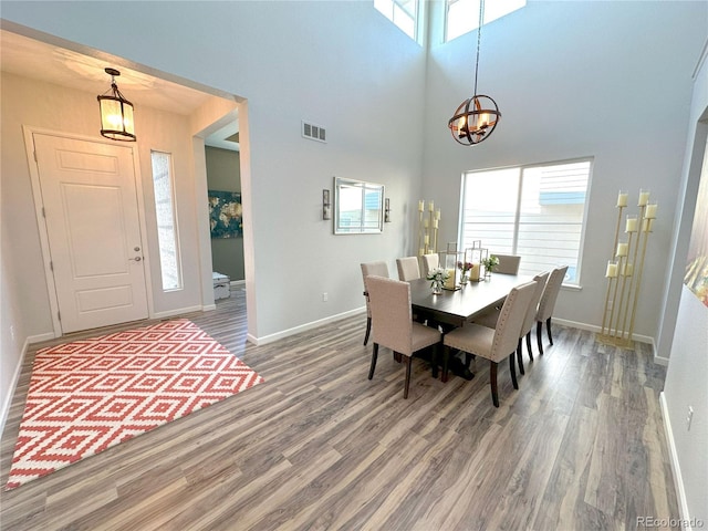 9482 Kendrick Way, Arvada, CO 80007 - dining room featuring a chandelier, wood finished floors, baseboards, and a towering ceiling