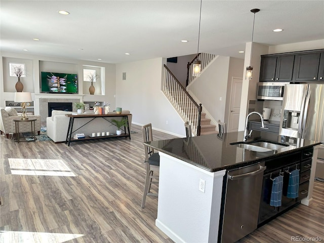 9482 Kendrick Way, Arvada, CO 80007 - kitchen featuring stainless steel appliances, wood finished floors, a kitchen island with sink, a kitchen bar, and recessed lighting