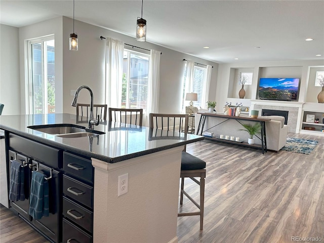 9482 Kendrick Way, Arvada, CO 80007 - kitchen featuring wood finished floors, a kitchen breakfast bar, a center island with sink, hanging light fixtures, and recessed lighting