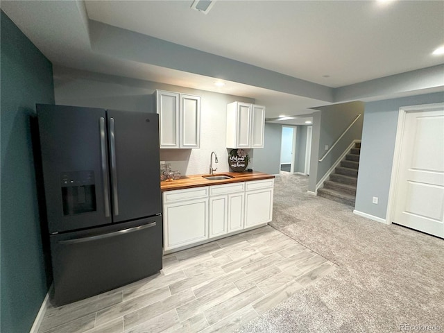9482 Kendrick Way, Arvada, CO 80007 - kitchen with black fridge with ice dispenser, butcher block countertops, white cabinets, light wood-type flooring, and recessed lighting