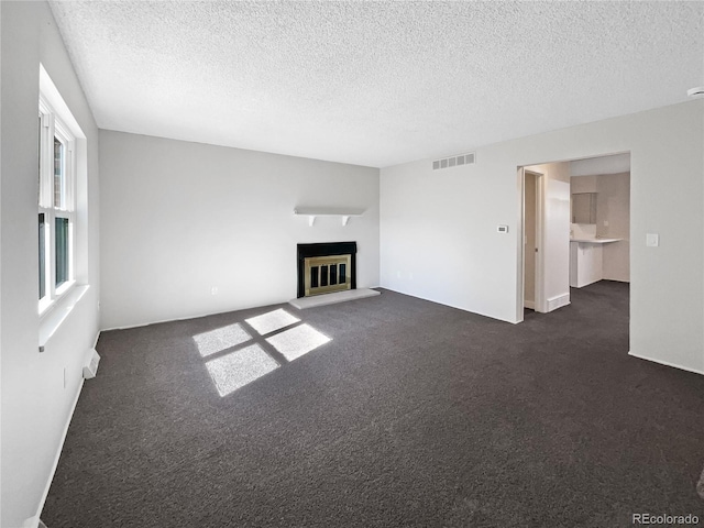 unfurnished living room featuring a textured ceiling and dark carpet