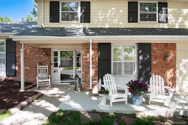 6624 S Sycamore St, Littleton, CO 80120 - property entrance featuring brick siding, a shingled roof, and a porch