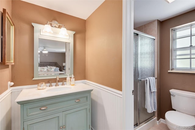 6624 S Sycamore St, Littleton, CO 80120 - bathroom featuring a wainscoted wall, a stall shower, vanity, toilet, and ceiling fan