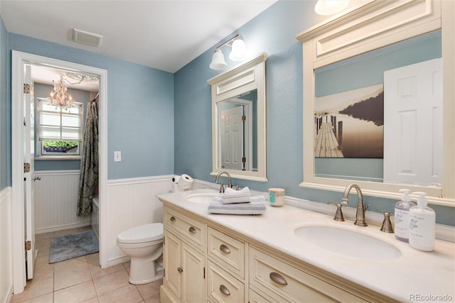6624 S Sycamore St, Littleton, CO 80120 - full bath with tile patterned floors, a wainscoted wall, double vanity, toilet, and a chandelier