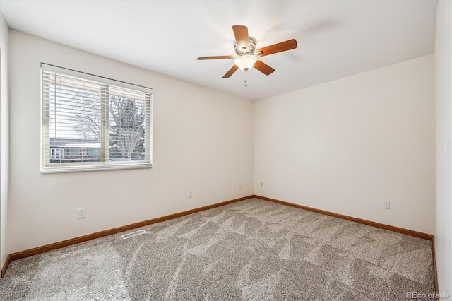 empty room with carpet, visible vents, ceiling fan, and baseboards