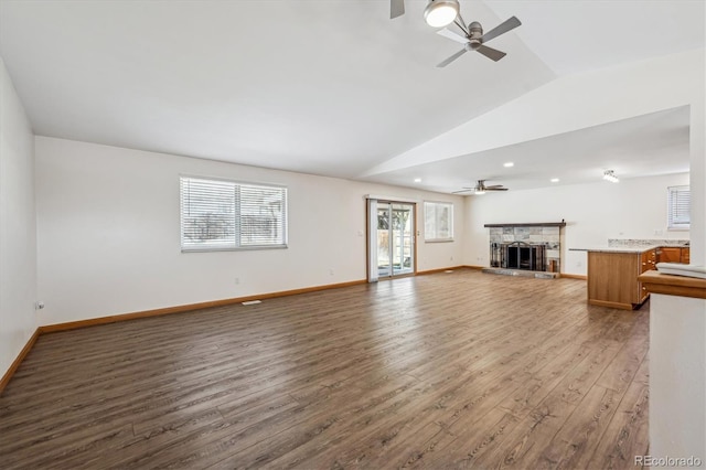 unfurnished living room featuring baseboards, a ceiling fan, wood finished floors, vaulted ceiling, and a fireplace