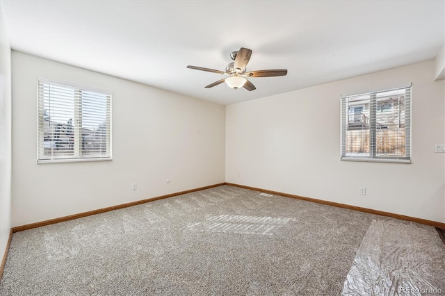 empty room with a ceiling fan, baseboards, and carpet flooring