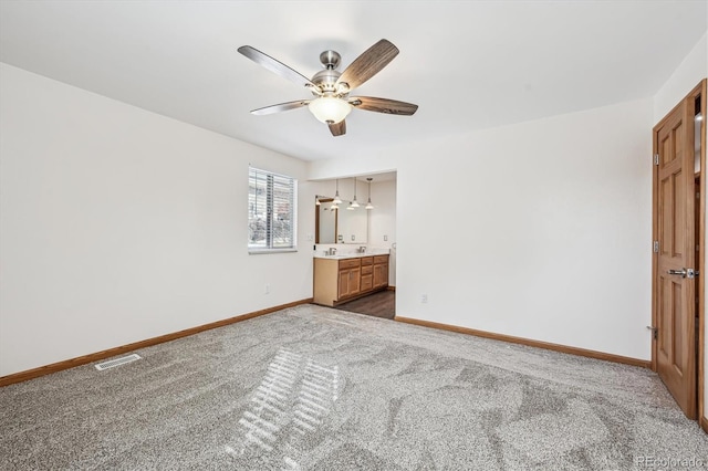 unfurnished bedroom with visible vents, dark carpet, ensuite bathroom, a ceiling fan, and baseboards