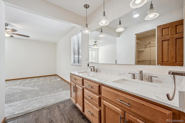 full bathroom featuring double vanity, baseboards, a sink, and wood finished floors