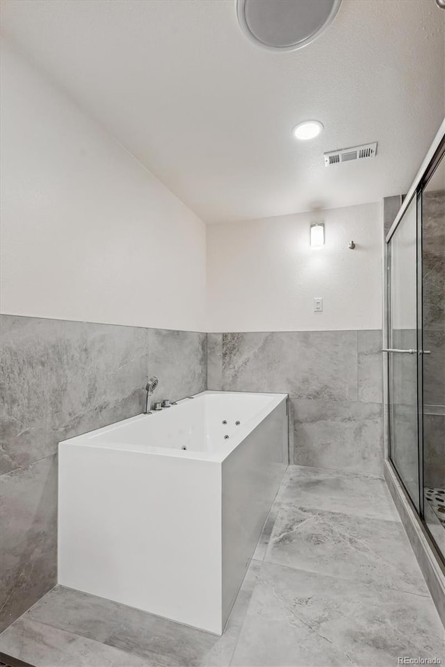 full bath featuring a stall shower, visible vents, a bath, marble finish floor, and tile walls