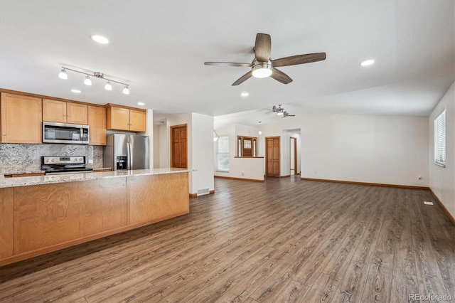 kitchen featuring stainless steel appliances, vaulted ceiling, decorative backsplash, and wood finished floors