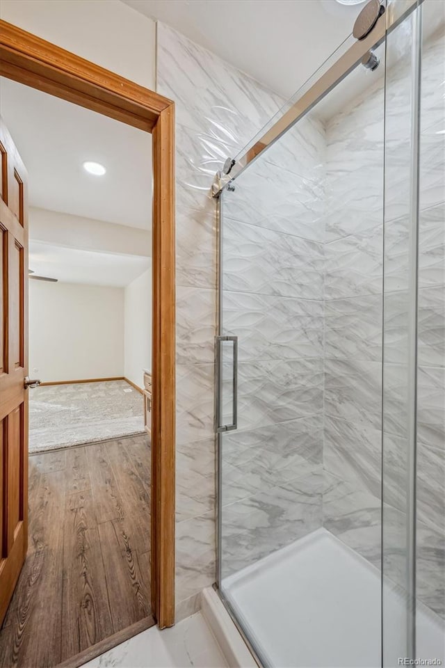 full bath featuring a marble finish shower and wood finished floors