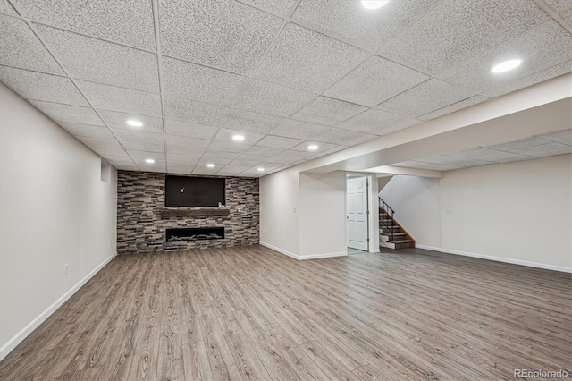 finished below grade area featuring baseboards, stairway, wood finished floors, a fireplace, and recessed lighting