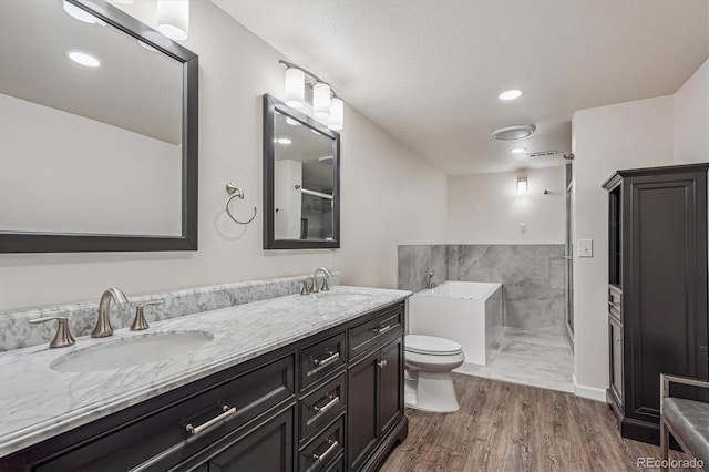 bathroom featuring a tub to relax in, double vanity, a sink, and wood finished floors