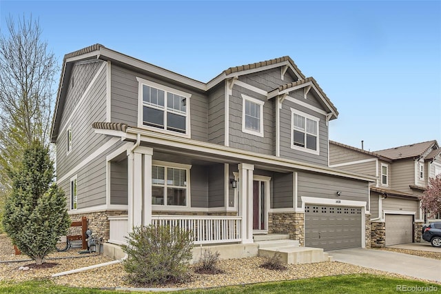 craftsman inspired home featuring a porch, a garage, stone siding, and concrete driveway