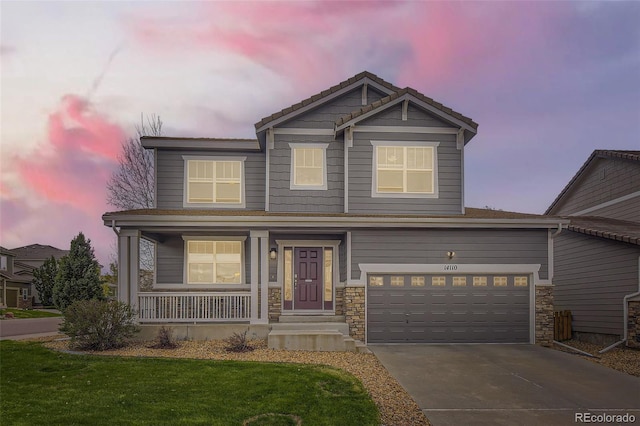 view of front of home featuring covered porch, stone siding, concrete driveway, and a front yard