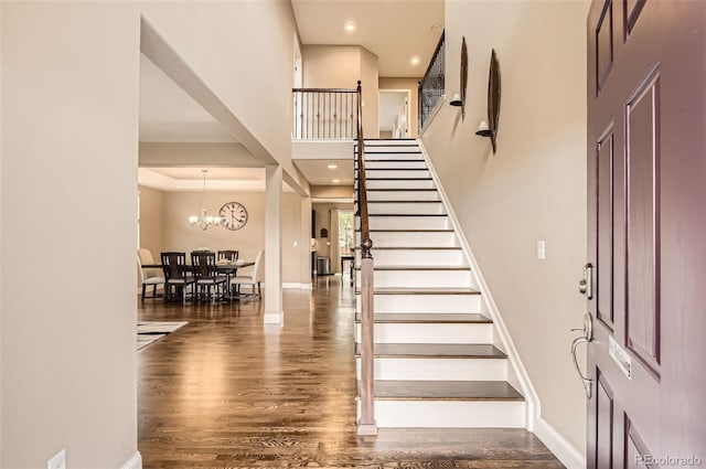 foyer with wood finished floors, stairway, baseboards, a high ceiling, and recessed lighting