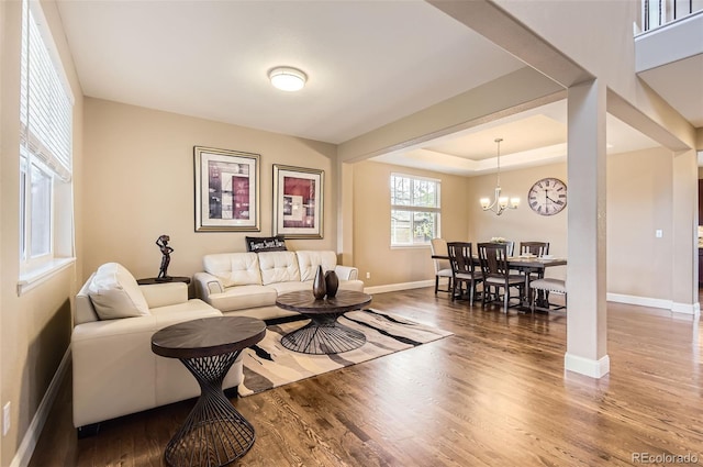 living area with baseboards, wood finished floors, and a notable chandelier