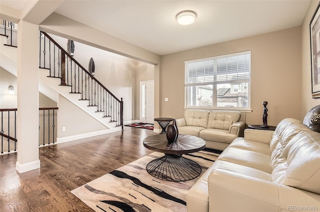 living room with baseboards, wood finished floors, and stairway