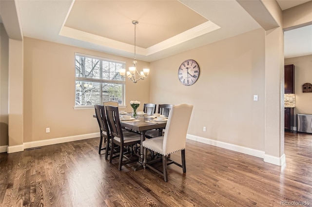 dining space with baseboards, a tray ceiling, dark wood-style flooring, and a notable chandelier