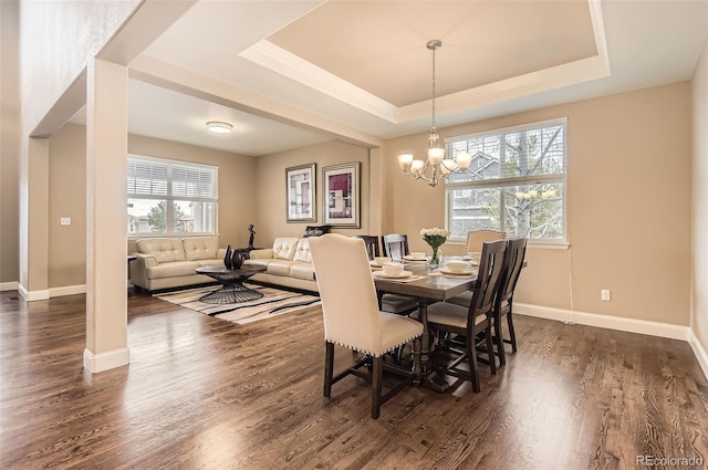 dining room with an inviting chandelier, a raised ceiling, and dark wood-style flooring
