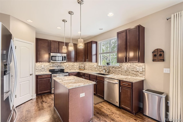 kitchen featuring dark brown cabinetry, a center island, tasteful backsplash, a sink, and stainless steel appliances