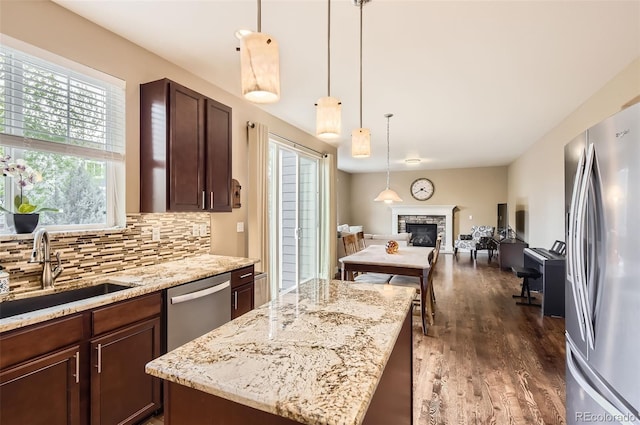 kitchen with a sink, dark wood finished floors, stainless steel appliances, open floor plan, and tasteful backsplash