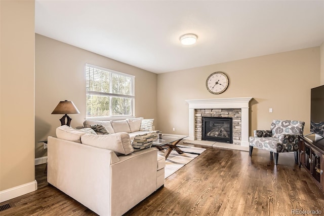 living area featuring baseboards, wood finished floors, and a fireplace