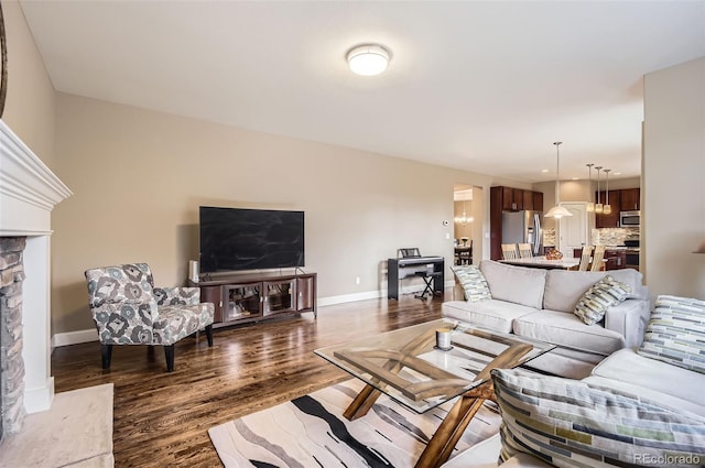 living room featuring baseboards, dark wood finished floors, and a fireplace