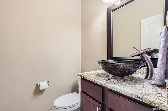 half bath featuring vanity and toilet
