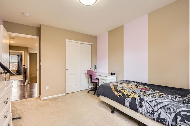 bedroom featuring light colored carpet, baseboards, and a closet