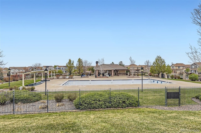 view of swimming pool with fence, a yard, and a residential view