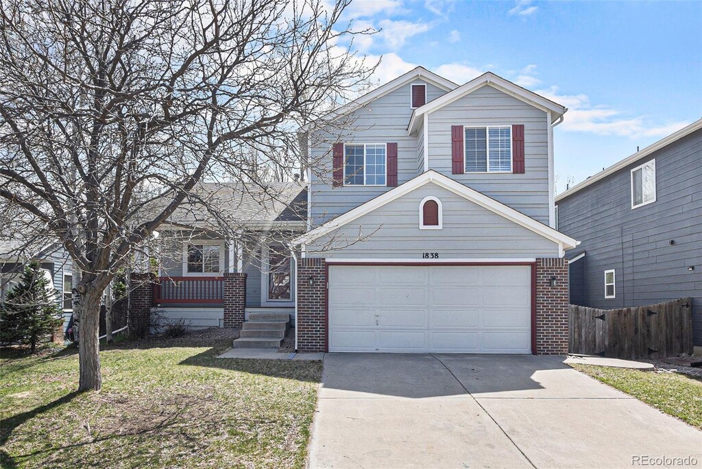 1838 Wilson Cir, Erie, CO 80516 - view of front of property with a front yard, fence, brick siding, a garage, and concrete driveway